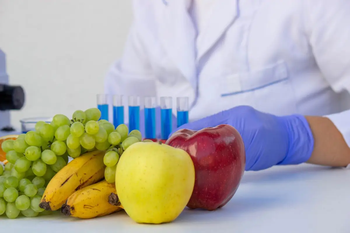 Frutas, legumes e tubos de ensaio em contexto laboratorial, representando a análise genética aplicada à alimentação personalizada.