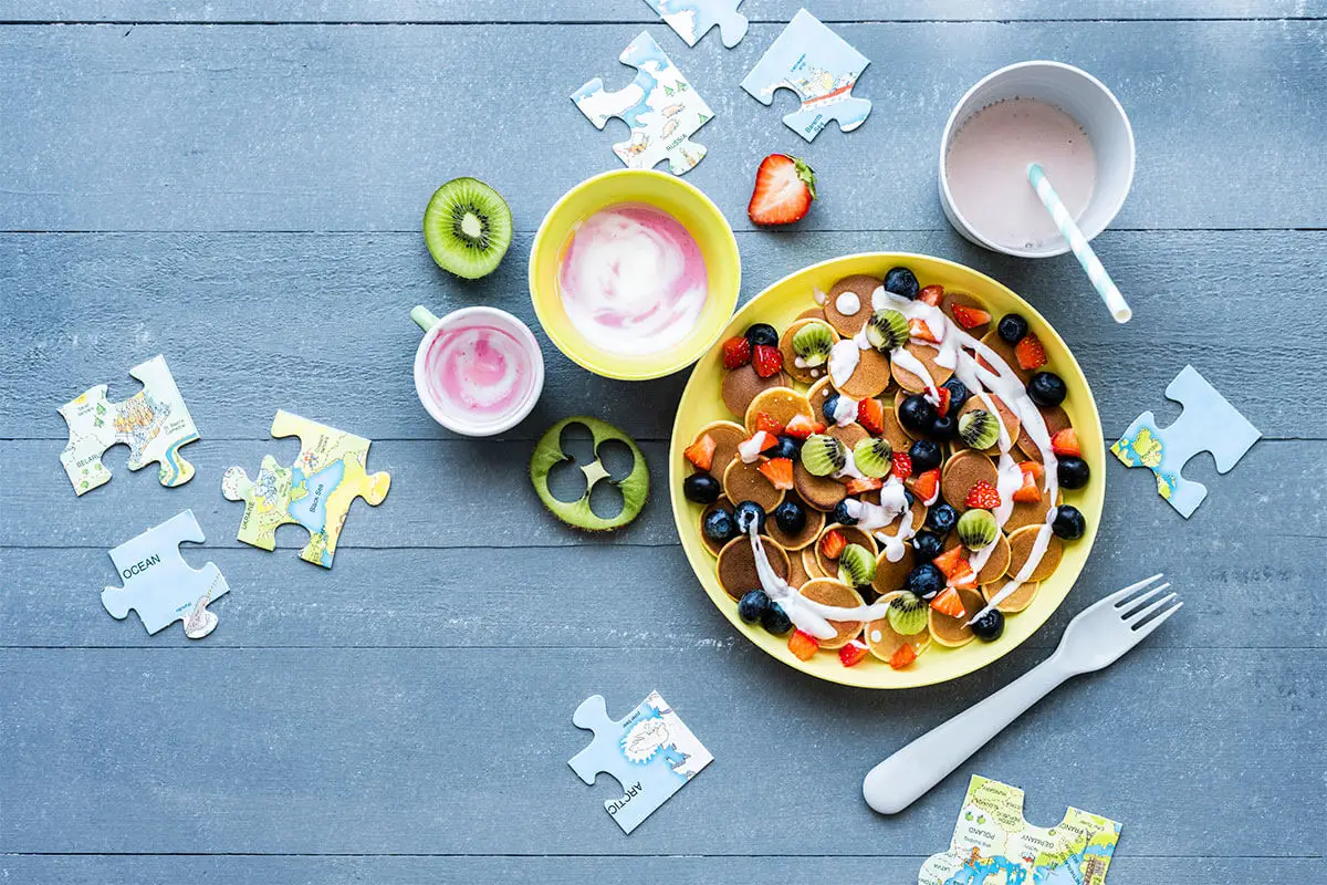 Alimentação saudável infantil com fruta fresca e pequeno-almoço nutritivo.