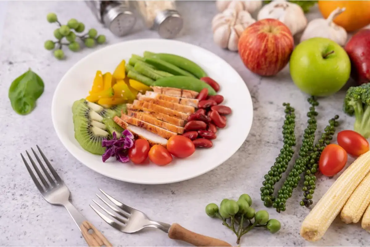 Prato equilibrado com frango, legumes, fruta e feijão recomendado para uma alimentação saudável.